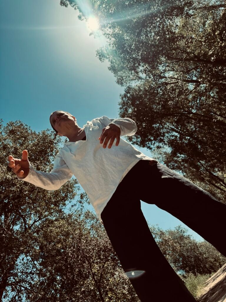 Persona mirando el cielo bajo árboles